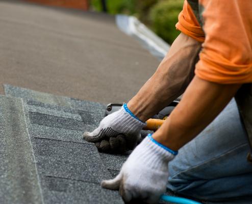 Roofing technician installing composite shingles.